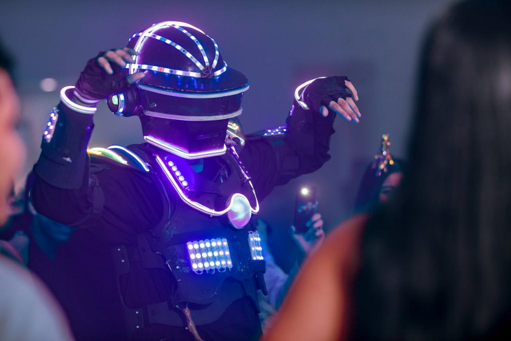 A performer in an illuminated LED suit entertains a vibrant crowd at night.