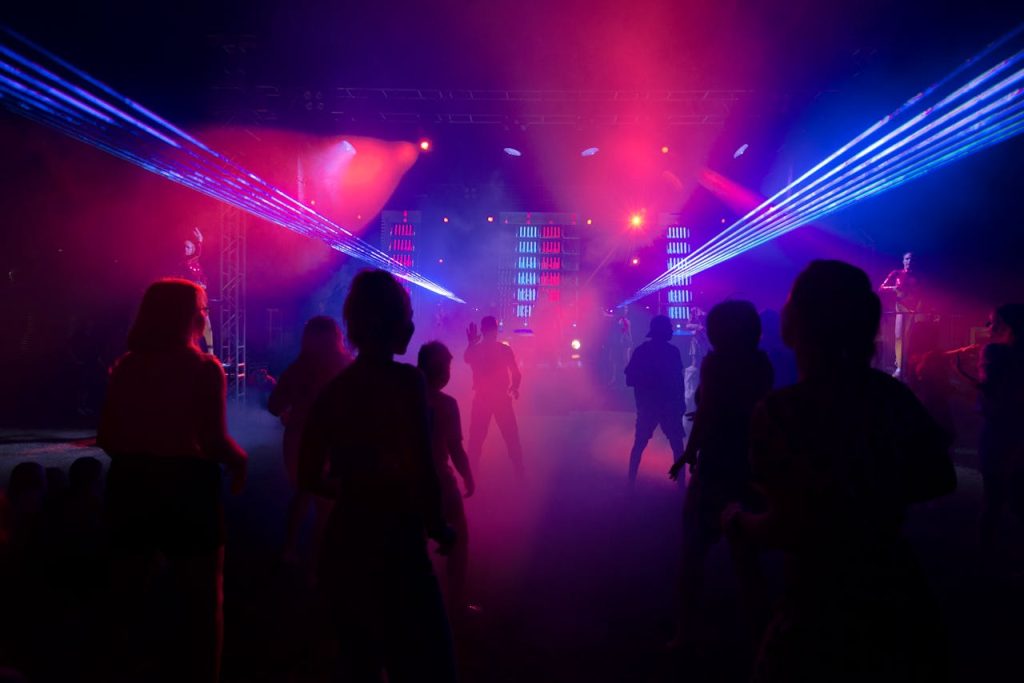 Energetic dance floor illuminated by colorful laser lights and silhouettes at a vibrant nightclub party.
